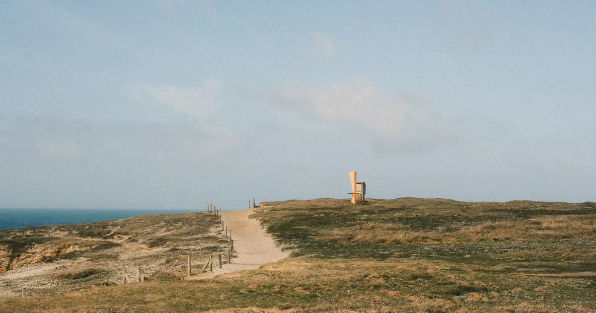 An open coastal footpath under a pale blue sky