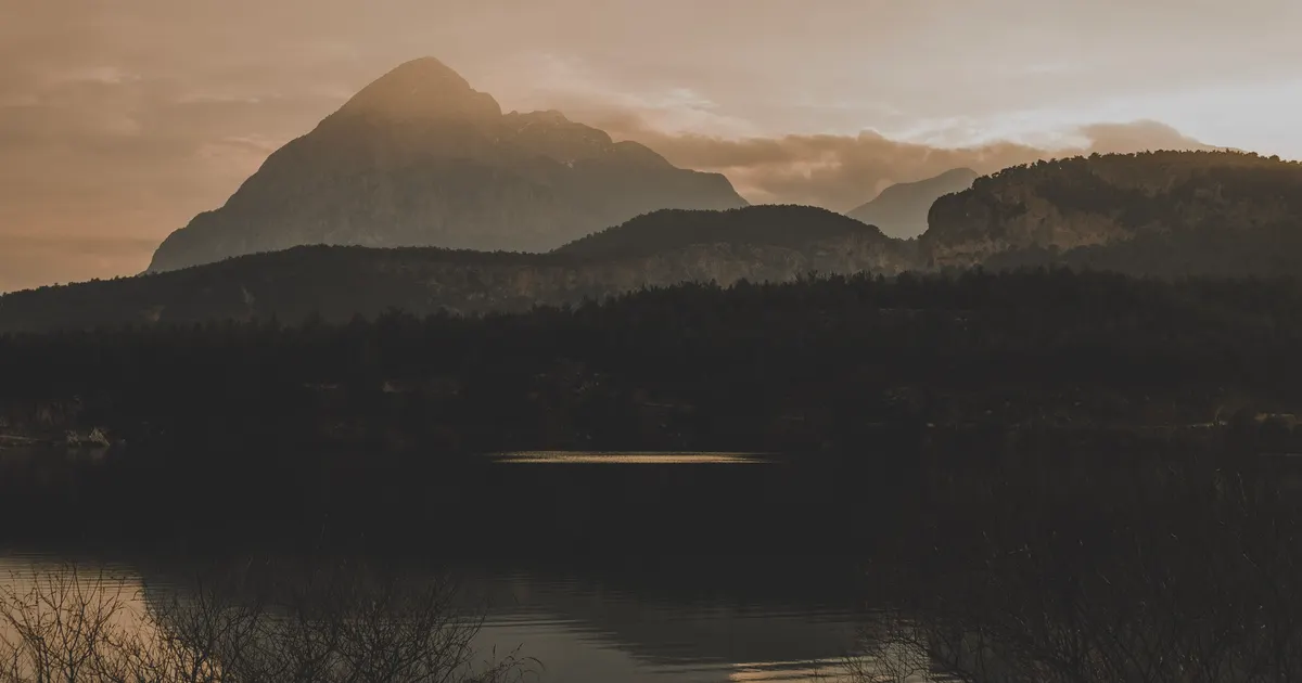 Layered mountain silhouettes above a quiet lake